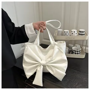 Dettaglio della borsa tote in pelle bianca con fiocco grande e manici lunghi