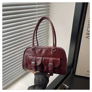 Détail du sac à main bordeaux avec deux poches à boucles et de longues anses fines