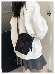 Detail of black nylon drawstring crossbody bag with orange fashion tag and embossed logo