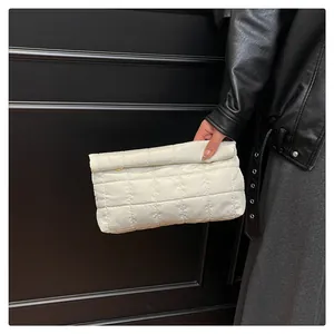 Close-up of white quilted puffer envelope bag with geometric stitching texture