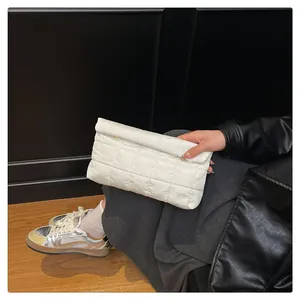Detail of white quilted fold-over clutch showing padded texture and minimalist design