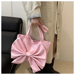 Dettaglio di borsa tote rosa acceso con grande fiocco decorativo e manici in pelle