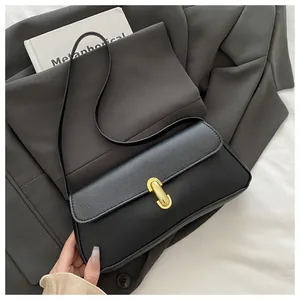 Detail shot of black lychee-textured leather surface and golden metal lock on handbag