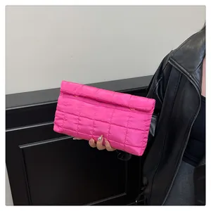 Close-up of rose pink quilted clutch bag with grid pattern and gold hardware clasp