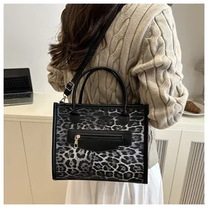Close-up of leopard print tote bag with black leather front pocket on a model for work