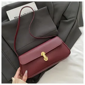 Detail of burgundy pebbled leather handbag with elegant gold U-shaped metal buckle