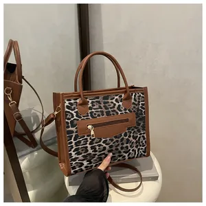 Detail view of leopard print crossbody bag with brown leather trim and golden zipper