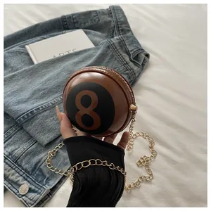 Close-up of billiard ball no.8 design handbag with gold chain strap held in hand