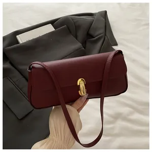 Detail of burgundy pebbled leather handbag with elegant gold metal twist lock