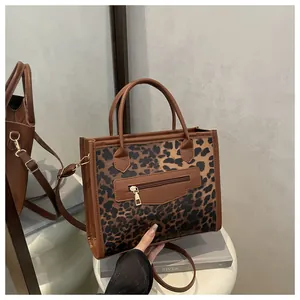 Detail of leopard print tote bag with brown leather trim and metal zip front pocket