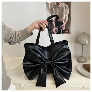 Dettaglio di una borsa tote in pelle nera con grande fiocco decorativo e doppi manici