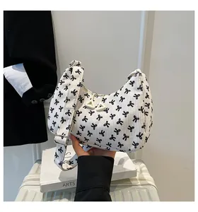 Close-up of white corduroy hobo bag with black bow print and adjustable strap