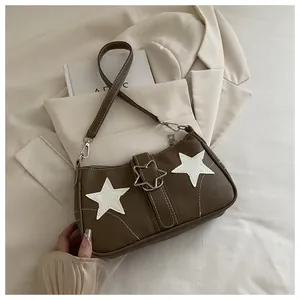 Detail of star-shaped metallic buckle and star patches on a brown leather shoulder bag