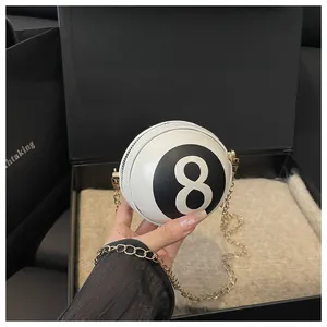 Detail of round 8-ball bag with gold chain strap on premium gift box background