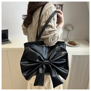 Dettaglio della borsa tote nera opaca con un grande fiocco e un elegante spallina sottile