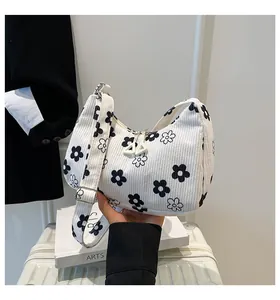 Detail of white corduroy hobo bag with daisy floral prints and dual zipper closure