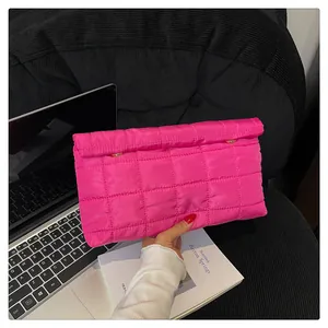 Detailed view of the fuchsia quilted envelope clutch bag with golden magnetic buttons