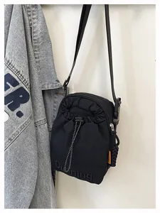 Detail of black sporty crossbody bag with drawstring closure and orange fashion label