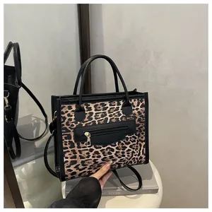 Detail of leopard print tote bag with black leather trim and gold hardware on a stool