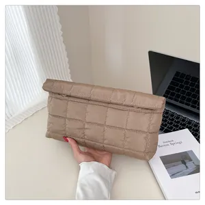 Detail shot of the quilted texture and flap closure on the coffee brown puffer clutch bag