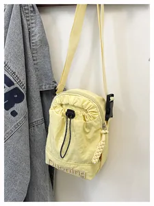 Close-up of a yellow nylon crossbody bag featuring Duoning embroidery and drawstring pocket