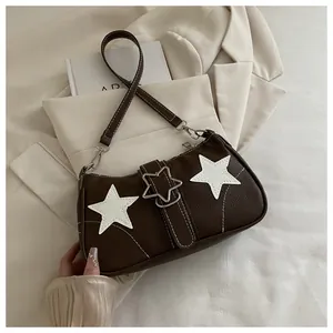 Detail of star-shaped metal buckle and white star patches on brown leather handbag