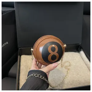 Detail view of mini round 8-ball crossbody bag with gold chain in a premium gift box