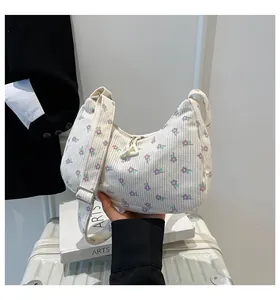 Close-up of cream floral corduroy shoulder bag with metal buckle and zipper detail