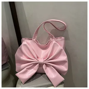 Dettaglio della borsa tote in pelle PU lucida rosa con un grande fiocco decorativo