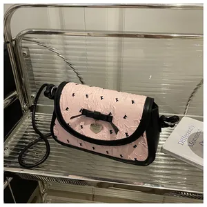 Detail of pink and black contrast crossbody bag with bow decoration and heart metal pendant