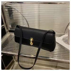 Detail shot of black litchi grain leather texture and gold metal lock buckle on the handbag