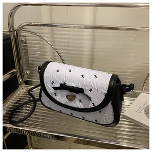 Close-up of bow knot design and heart pendant on black and white mini square bag