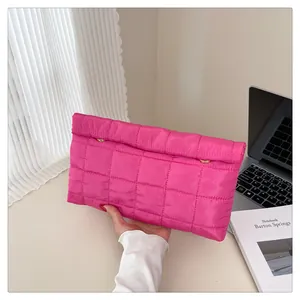 Detail of bright pink quilted envelope clutch with golden hardware and luxury texture