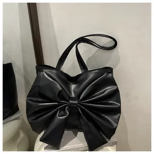 Dettaglio della borsa tote in pelle PU nera con grande fiocco decorativo e spalline sottili