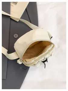 Detail view of the cream nylon crossbody bag showing the interior lining and zip closure