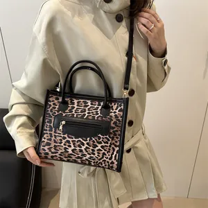 Leopard print crossbody handbag with black handles and shoulder strap on model