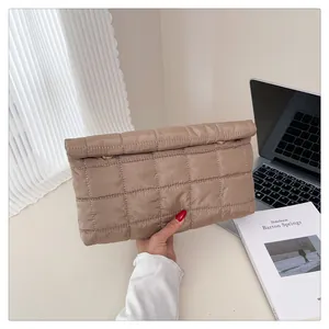 Detail of khaki quilted envelope clutch bag with metal ring shown in a modern office setting