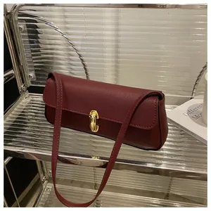Detail of burgundy textured leather shoulder bag with elegant gold rectangle clasp lock