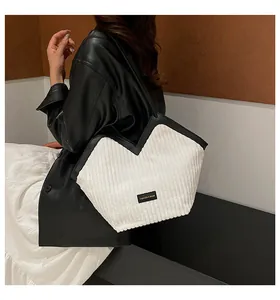 Detail of white corduroy tote bag with black leather straps on a fashion model