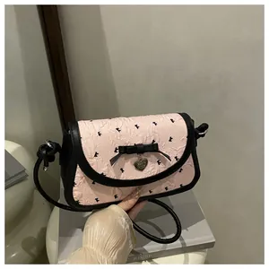 Detail of pink bow-patterned bag with black ribbon and silver heart pendant charm