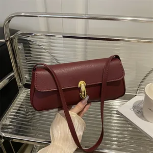 Elegant deep red pebble leather shoulder bag with a stylish gold lock on a chic chair