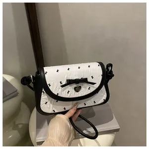 Close-up of contrast crossbody bag with bow detail and heart-shaped metal pendant