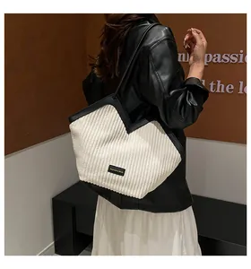 Detail of V-shaped corduroy tote bag with black leather straps and fashion label