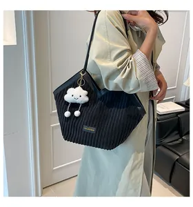 Detail of black corduroy tote bag with cloud charm on model wearing a beige trench coat