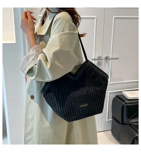 Detail of black corduroy tote bag featuring striped texture and fashion brand plaque