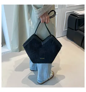 Close-up of black corduroy tote bag with V-shaped opening and gold metal brand plate