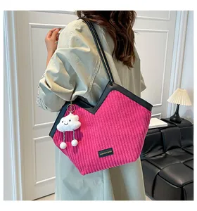 Detail of fuchsia corduroy tote bag featuring black leather handles and cloud charm