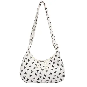 White corduroy crossbody bag with black bow print and adjustable shoulder strap
