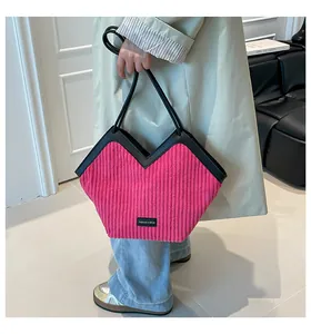 Detail view of pink corduroy tote bag with black leather handles and fashion logo