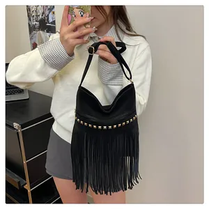 Détail d'un sac à bandoulière noir à franges avec rivets dorés et sangle réglable